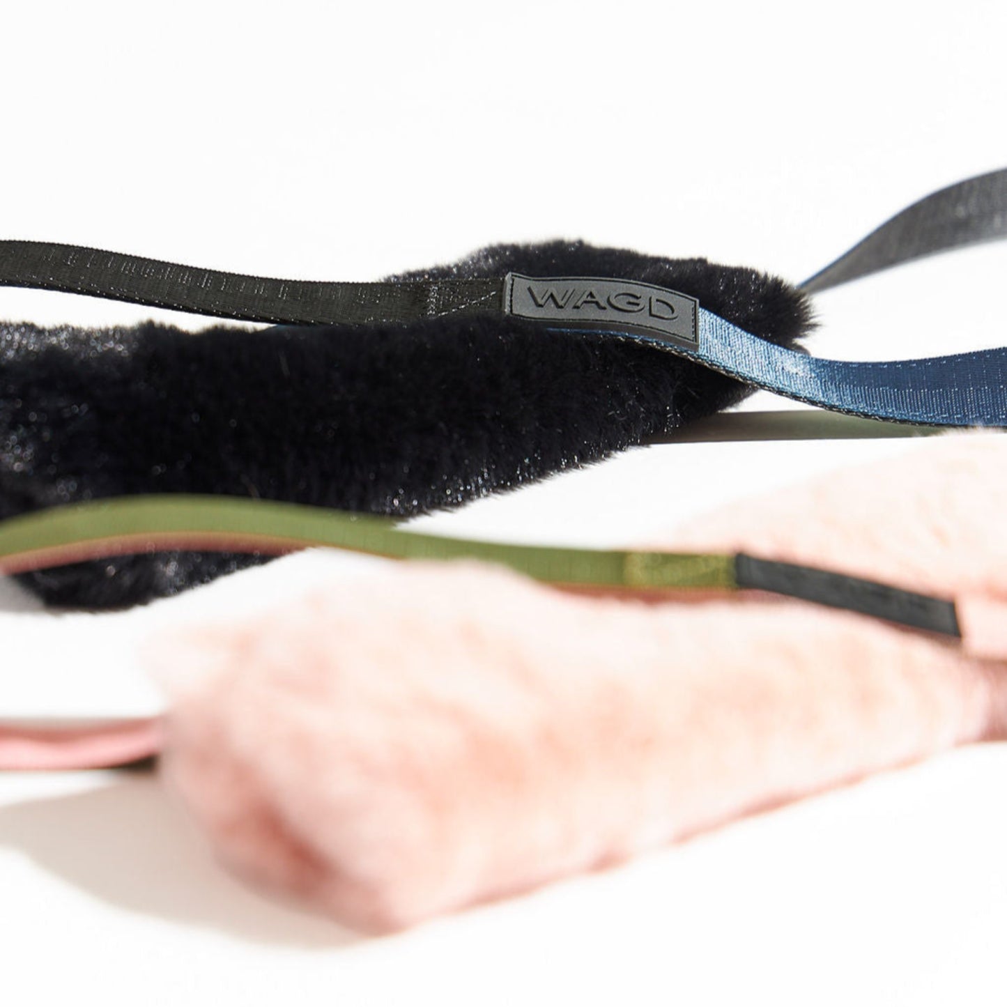 Side view of 2 dog tug toys with rubber logos and pink an black fur