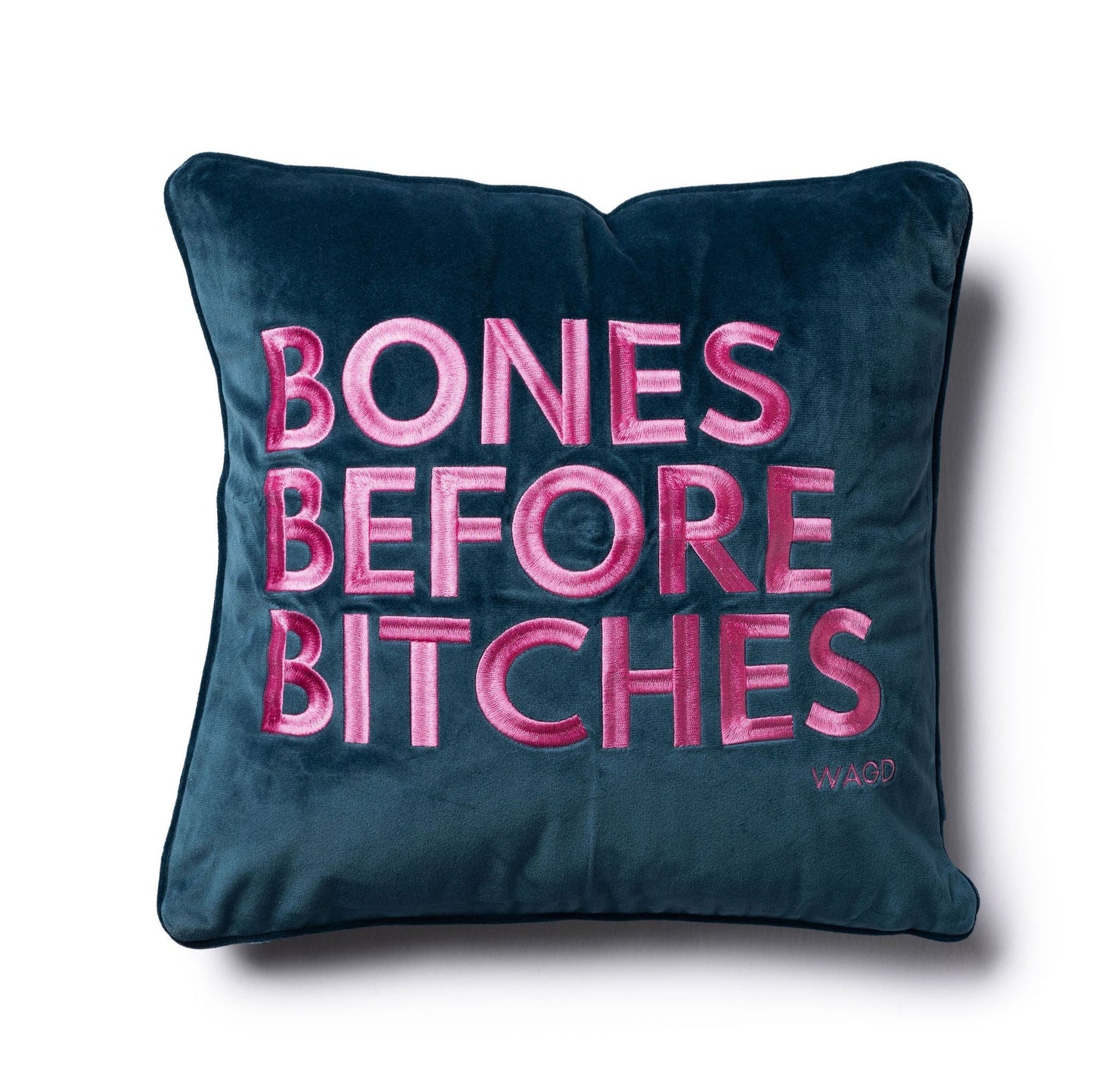 velvet square pillow with Bones Before Bitches embroidered on to it. Peacock base with pink embroidery.