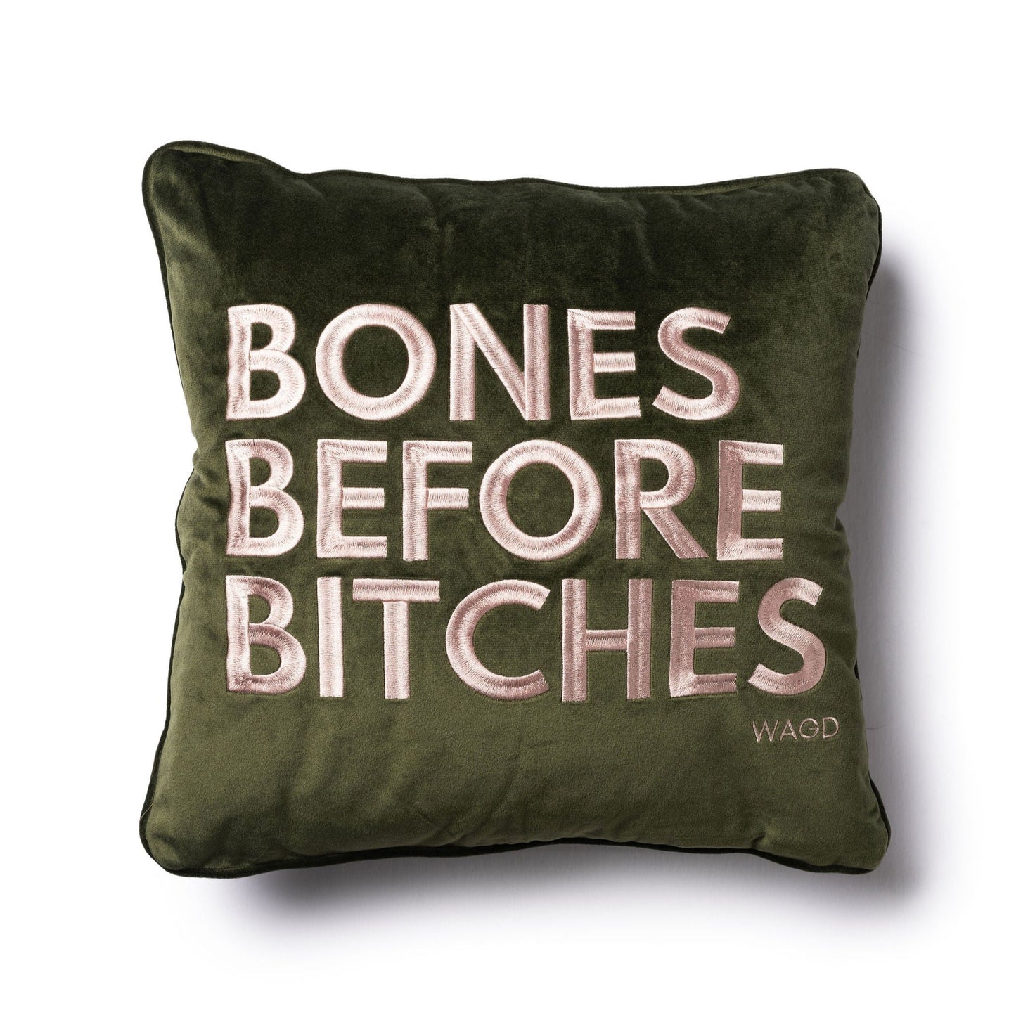 velvet square pillow with Bones Before Bitches embroidered on to it. Olive base with pink embroidery.