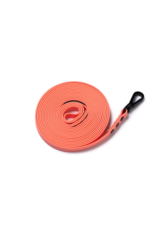Picture of a coral 5m rubber coated lead rolled up and laid flat on a white background.